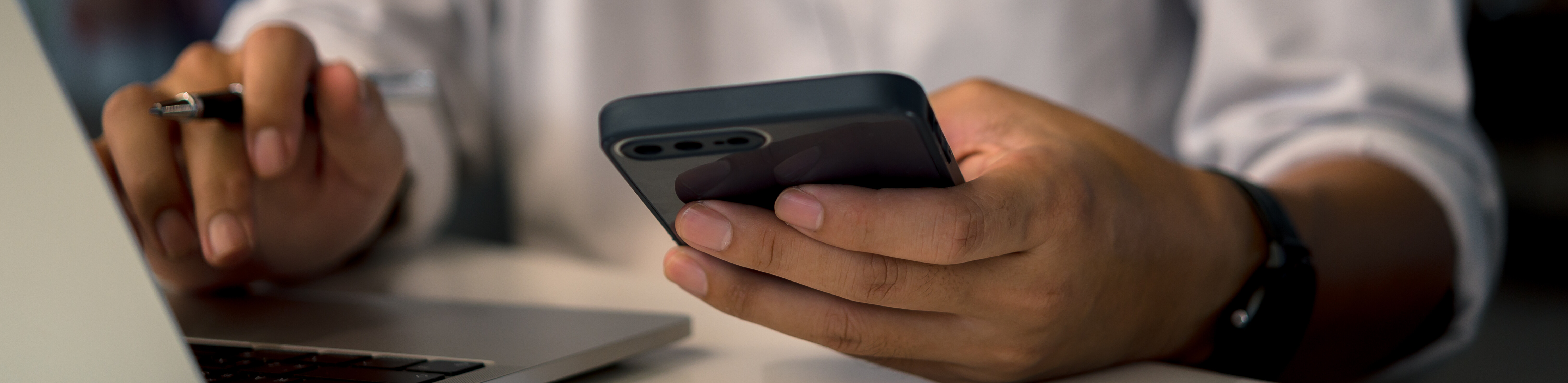 Bankverbindung mitteilen Person vor einem Laptop mit Handy trägt etwas ein